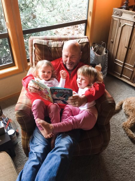 grandfather reading to cousin girls in matching pajamas