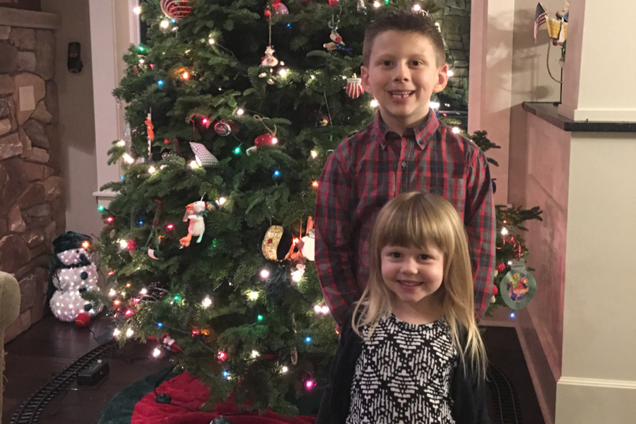 Brother and sister standing in front of Christmas tree