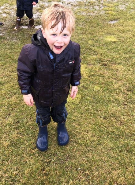 little boy soaking wet after playing in puddle