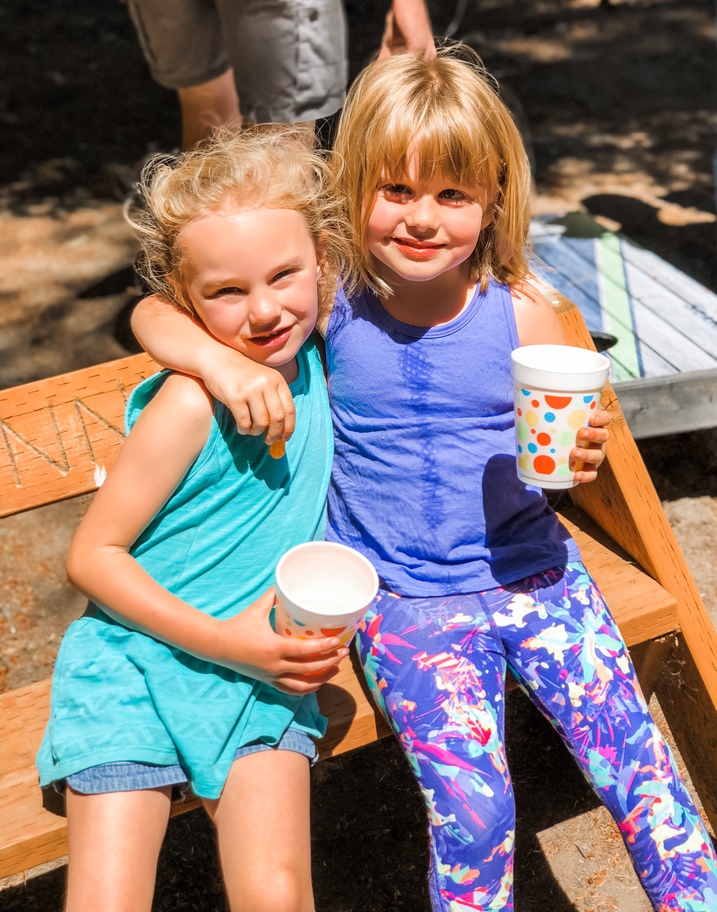 two girl cousins wrap arms around each other while eating cheetos