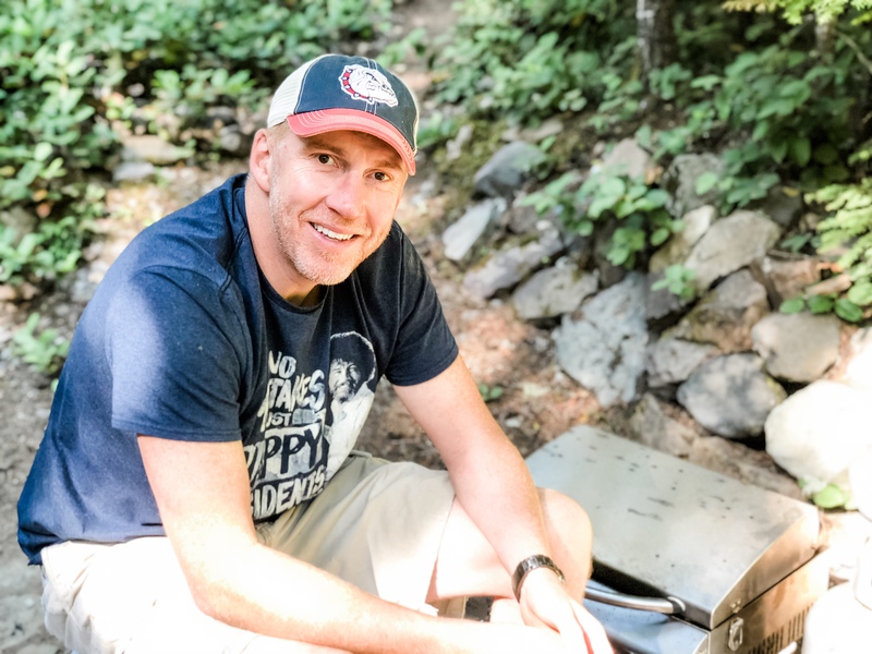 jeff sits at barbecue at cabin