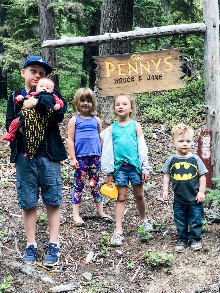 five grandkids stand at cabin sign together