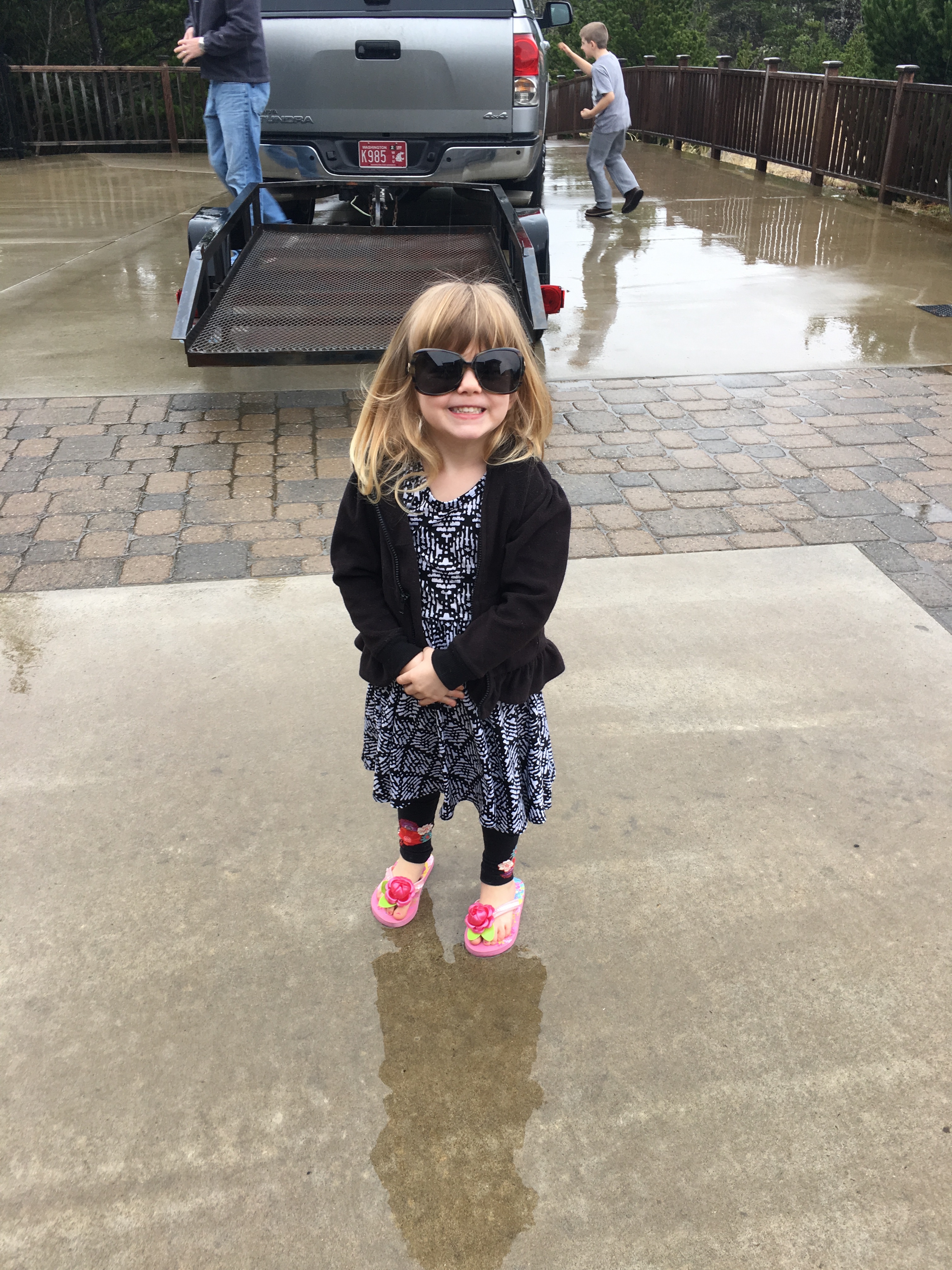 little girl in sunglasses and flip flops in the rain