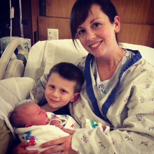 mother holds newborn and son in hospital