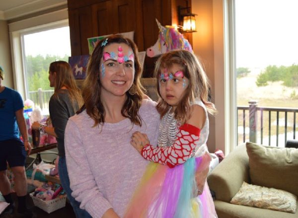 mother holds 5 year old daughter with unicorn face paint