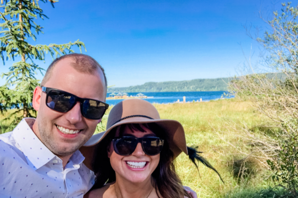 a couple stands in the sun with blue skies