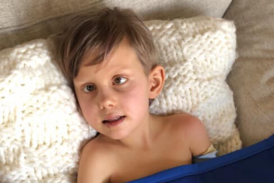 DIPG warrior Dylan lies on couch with quilt